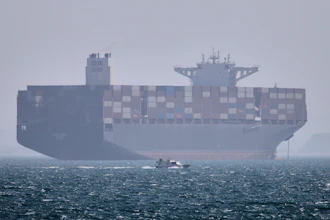 A container ship sits at anchor as a small motorboat passes in the Strait of Hormuz off Bandar Abbas, Iran, May 2, 2026.