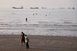 Men walk on the shoreline as people wade in the water in the Strait of Hormuz off Bandar Abbas, Iran, June 1, 2026.
