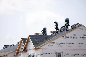 People work on the roof of a new housing development in Sandston, Va., June 6, 2025.