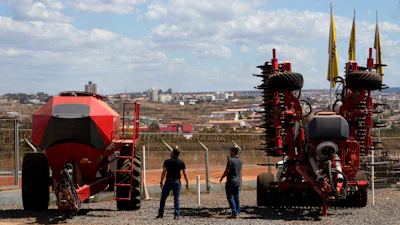 Salesmen walk among agricultural machinery displayed at an equipment dealership, Brasilia, Brazil, July 22, 2026.