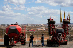 Salesmen walk among agricultural machinery displayed at an equipment dealership, Brasilia, Brazil, July 22, 2026.