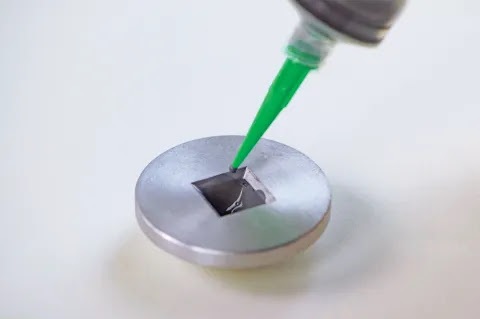 Green-handled applicator tool demonstrating application on circular metallic surface