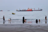 People spend time at a beach as commercial vessels are anchored in the Strait of Hormuz off Bandar Abbas, Iran, Aug. 5, 2026.