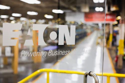 Eaton corporate logo and 'Powering Business Worldwide' tagline on glass window overlooking industrial warehouse facility