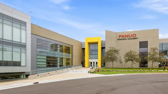 Modern FANUC Training Academy building with glass and tan facade, featuring yellow accent entrance and landscaping
