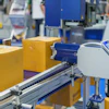 Yellow cardboard boxes moving on industrial conveyor belt in packaging facility with blue machinery